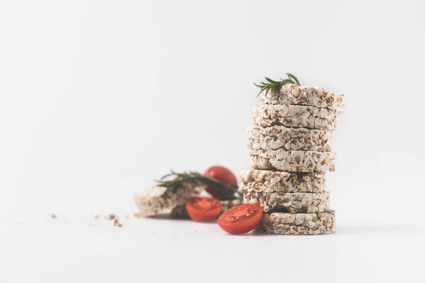 pila de pasteles de arroz con romero y tomates en la superficie blanca
 - Foto, imagen