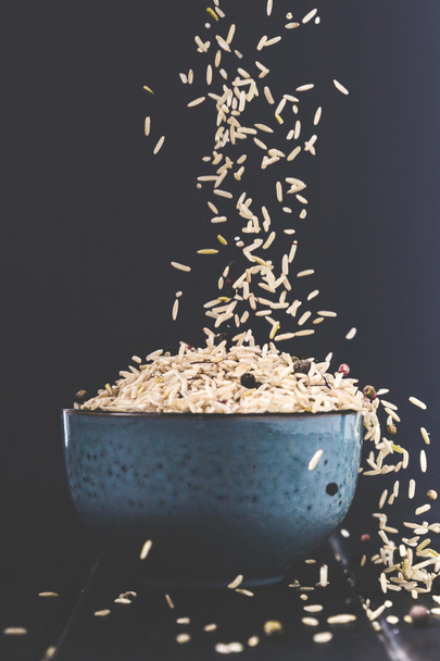 крупним планом шматок рису, що розливається в миску на чорному столі
 - Фото, зображення
