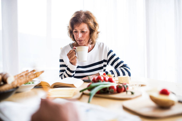 Senior vrouw eten ontbijt thuis. - Foto, afbeelding