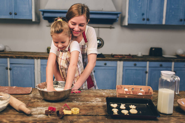 Cooking homemade cakes. Happy loving family are preparing bakery together. Mother and child daughter girl are cooking cookies and having fun in the kitchen. Roll the dough. - Фото, зображення