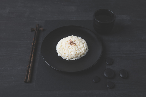 rice with cup of tea and chopsticks on black table - Fotoğraf, Görsel