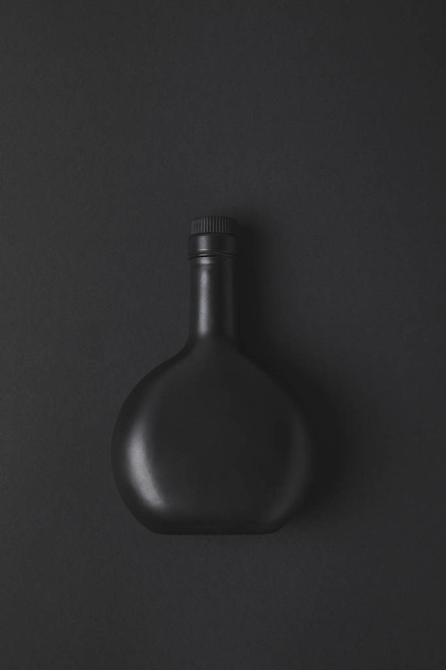 top view of empty bottle on black surface - Foto, afbeelding