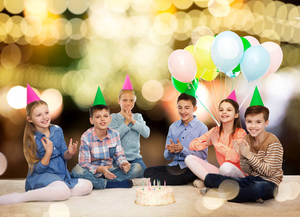 happy children in party hats with birthday cake - Zdjęcie, obraz