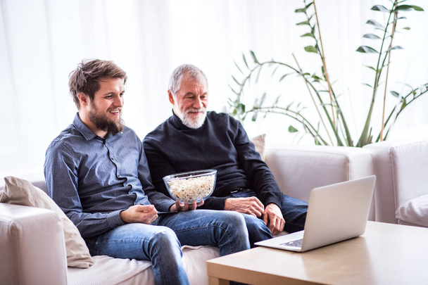 Hipster son and his senior father with laptop at home. - Photo, image
