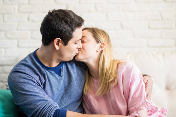 Primo piano di romantica giovane coppia baciarsi mentre si siede sul divano a casa
 - Foto, immagini