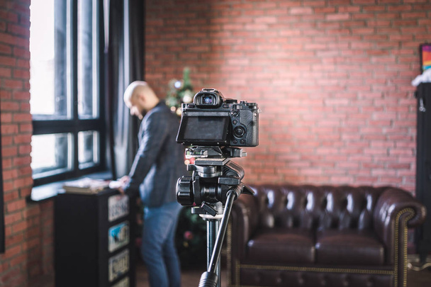 Man blogger prepares to record himself on video blog on the camera in studio - 写真・画像