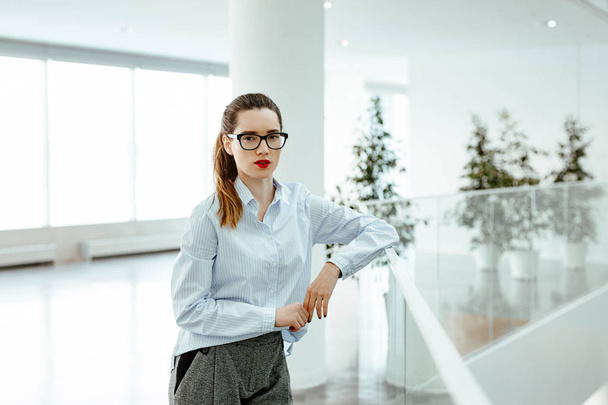 portrait  the business lady in stylish glasses and a trouser suit against the background of business center.  - Zdjęcie, obraz