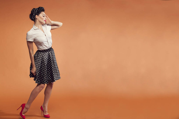 young woman in skirt on orange background - Foto, Imagen