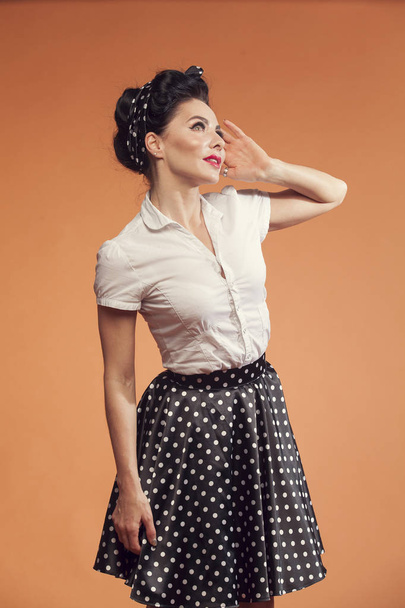 young woman in skirt polka dot on orange background - Zdjęcie, obraz