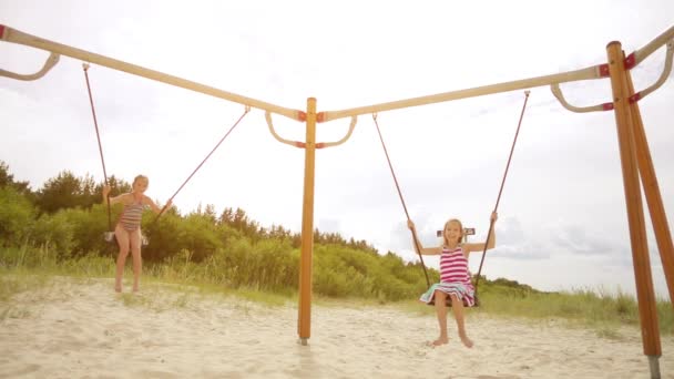 Slow Motion: Two little beautiful girls on swing Baltic Sea in Jurmala, Latvia. - Footage, Video