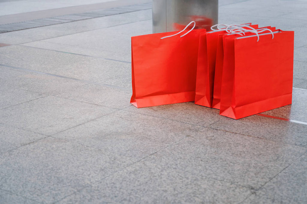 many colorful red paper shopping bags on floor in modern city background, black friday, winter sale, promotion, special offer and shopping online concept - Fotó, kép
