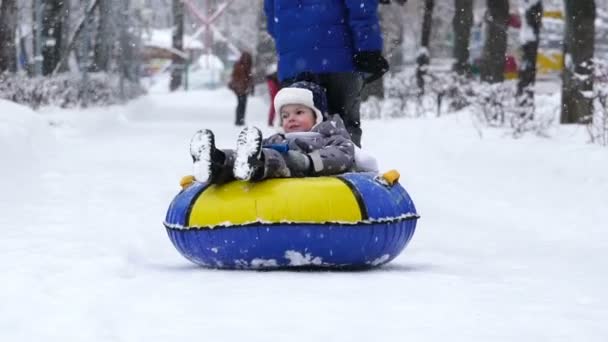 boy of two years rolling on tubing in the park in winter. - Footage, Video