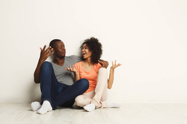 Афро-американская пара смотрит вверх, сидит на полу
 - Фото, изображение