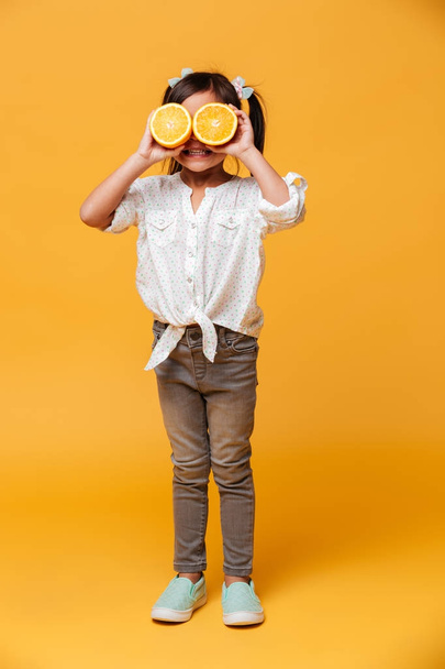 Little girl child covering eyes with orange. - Foto, afbeelding