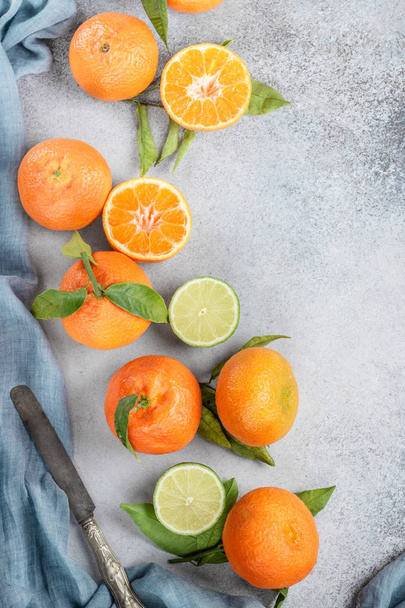 Citrus fruits with green leaves, tangerine and lime  on table - Fotografie, Obrázek