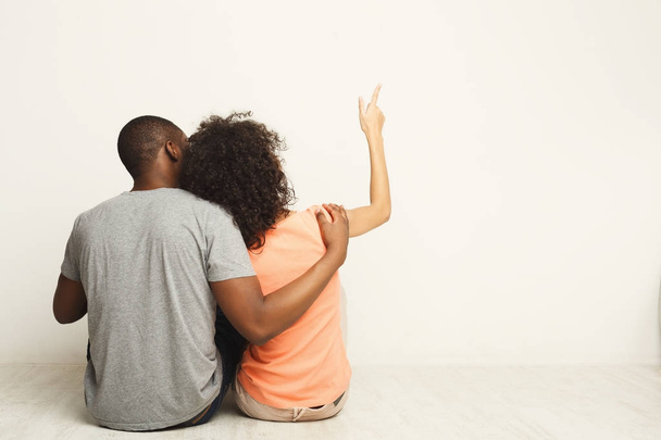 Афро-американская пара смотрит вверх, сидит на полу
 - Фото, изображение