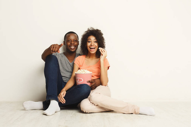 Sorridente coppia nera in attesa di film a casa sul pavimento
 - Foto, immagini