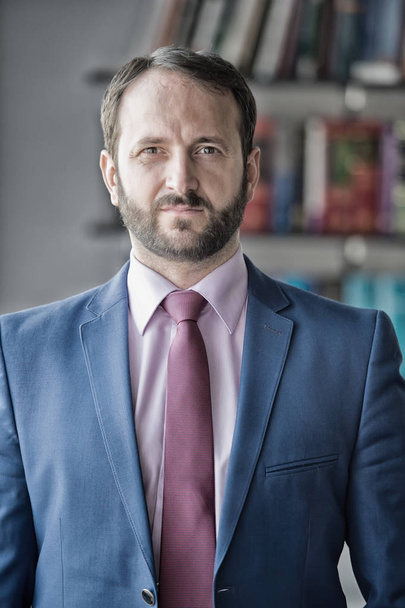 Career, profession, work. Businessman or director pose in office. Business, entrepreneurship concept. Fashion, style, dress code. Man with beard in blue jacket, shirt and tie, vintage filter - Valokuva, kuva
