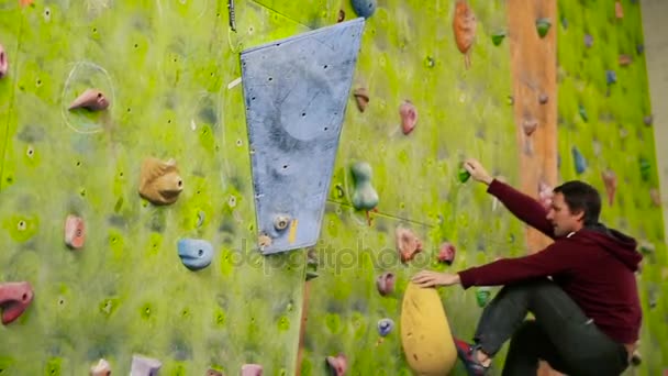 Professional boulder climbing on a steep wall and breaks down. The climbing wall. Climbing wall in the room. - Footage, Video