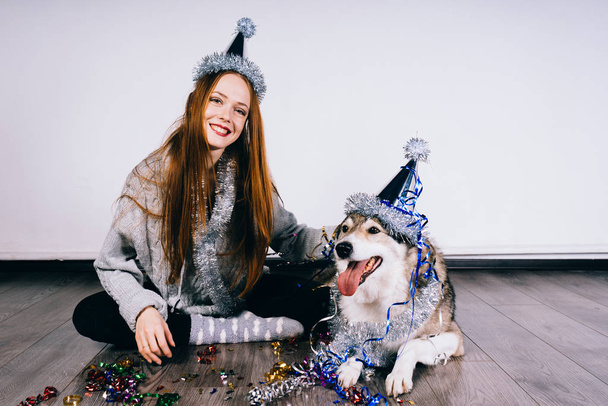 happy woman in festive cap sits next to dog - Foto, Imagen