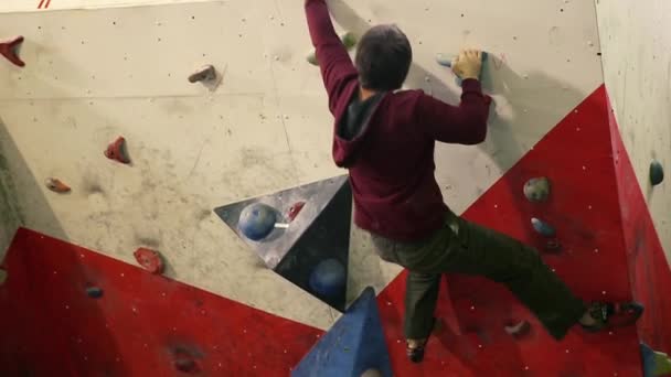 A rock climber climbs a steep wall and breaks down after a failed attempt to climb to the top. A climbing wall indoors. - Footage, Video