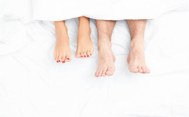 Close up of the feet of a couple on the bed. - Fotografie, Obrázek