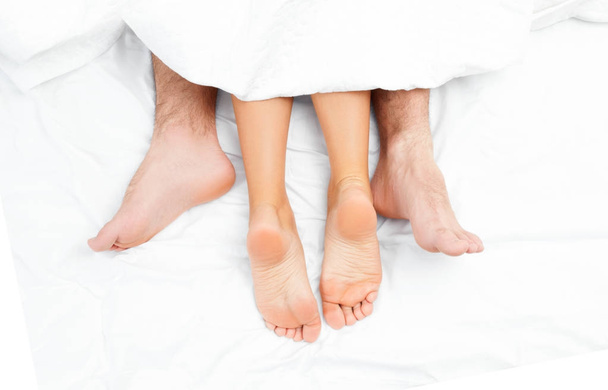 Close up of the feet of a couple on the bed. - Fotoğraf, Görsel