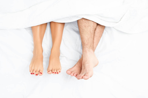 Close up of the feet of a couple on the bed. - Foto, imagen