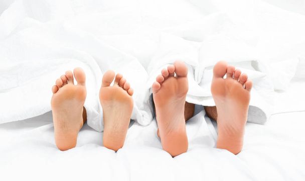 Close up of the feet of a couple on the bed. - Photo, Image