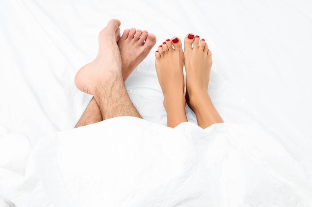 Close up of the feet of a couple on the bed. - Valokuva, kuva