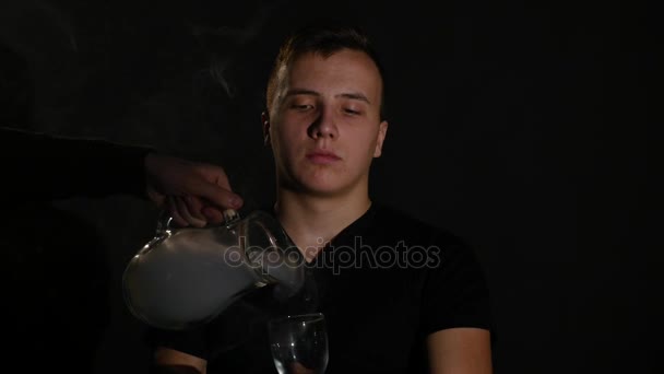 Man smoking electronic cigarette vapor on black background - Filmati, video