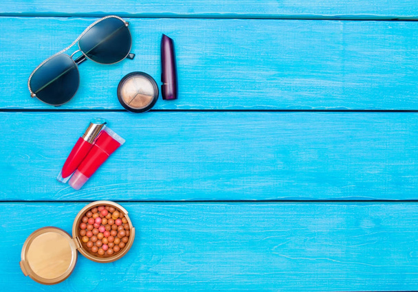 Makeup products on blue wood background, glasses. Flat Lay - Photo, Image