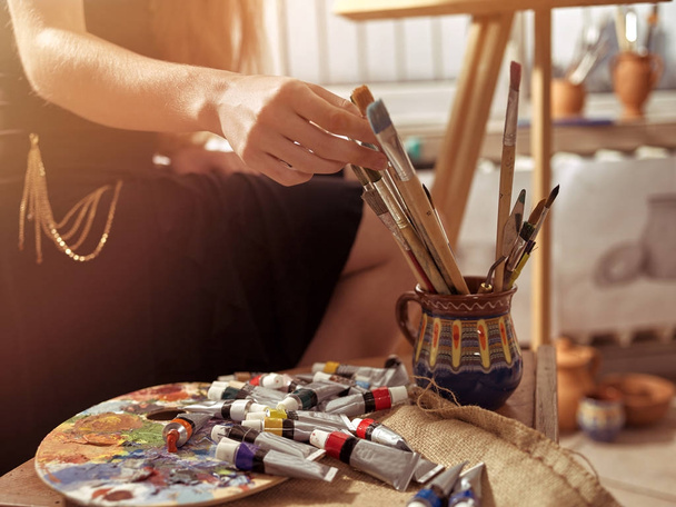 Artist painting on easel in studio. Girl paints with brush. - Valokuva, kuva