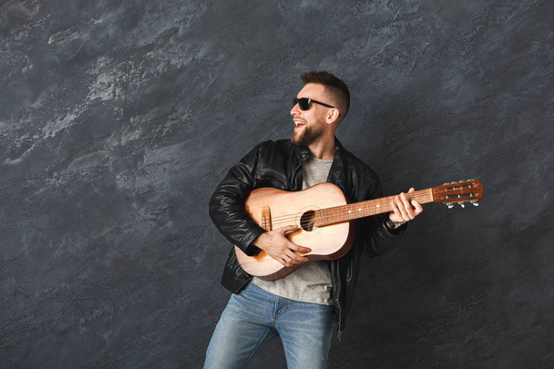 Bonito homem sorridente com guitarra posando em estúdio
 - Foto, Imagem