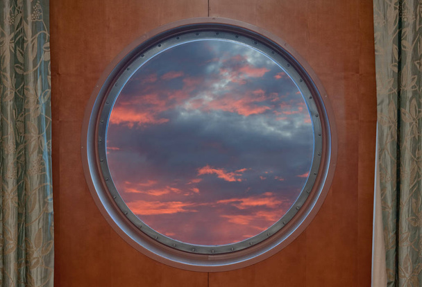 Sonnenuntergang durch das Bullauge eines Schiffes gesehen - Foto, Bild
