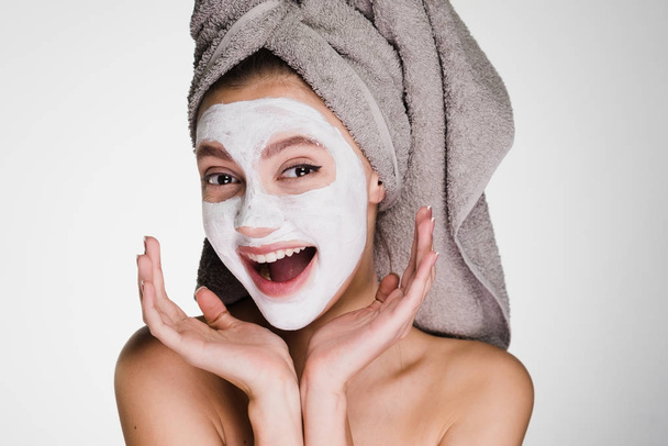 woman with a towel on her head applied a white mask to clean the skin of the face - Foto, imagen