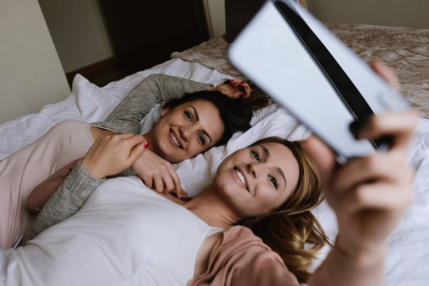 Gorgeous friends taking a selfie in the bedroom. - Zdjęcie, obraz