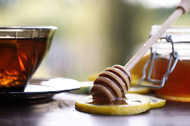 Fresh honey with a cup of black tea - Фото, изображение