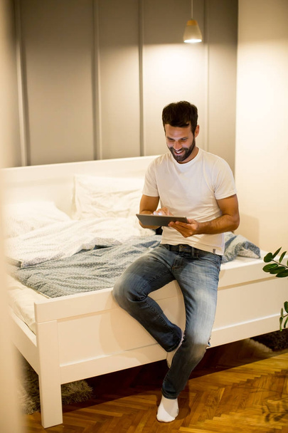 Νεαρός άνδρας με ψηφιακό tablet στο δωμάτιο - Φωτογραφία, εικόνα