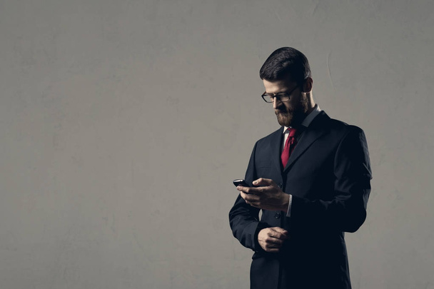 Businessman with smartphone standing over white wall. - Photo, image
