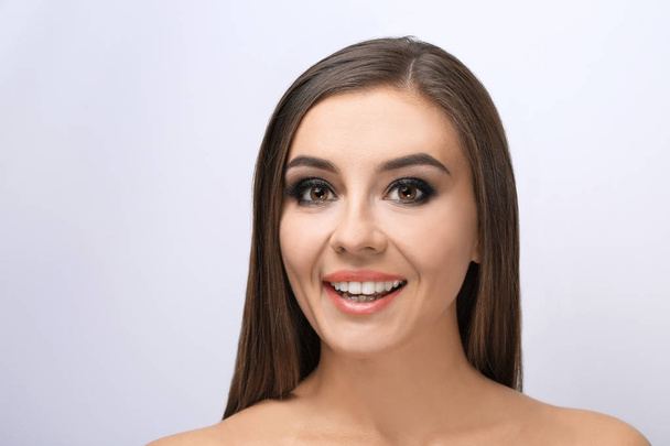Beautiful young woman with eyelash extensions on light background - Zdjęcie, obraz