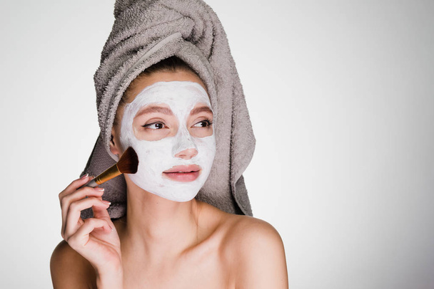 woman with a towel on her head applied a white cleansing mask - Фото, изображение