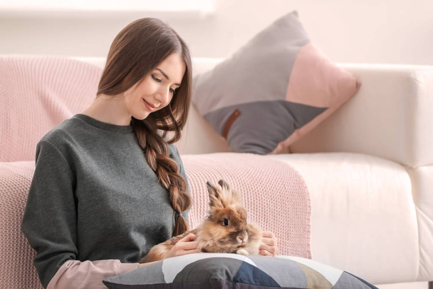 Beautiful young woman with pet rabbit at home - Fotó, kép