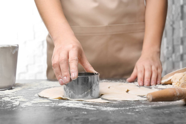 Woman cutting dough on table, closeup. Cooking dumplings - 写真・画像