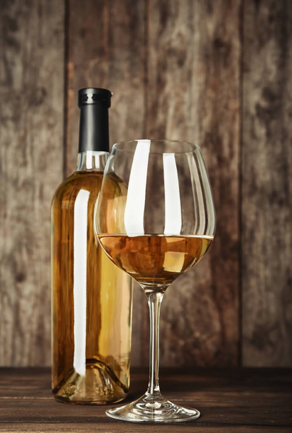 Bottle and glass with white wine on wooden table - Foto, imagen