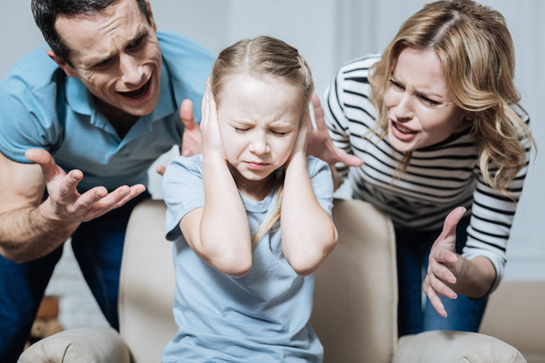 Unsmiling girl and her parents shouting at her - Foto, Bild