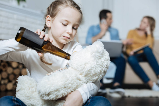 trauriges Mädchen schenkt ihrem Teddybär Bier - Foto, Bild