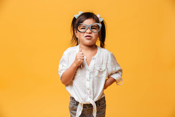 Funny little girl child holding fake glasses. - Foto, imagen