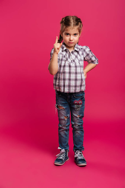 Serious little girl child standing isolated gesturing with finger. - Foto, Imagen