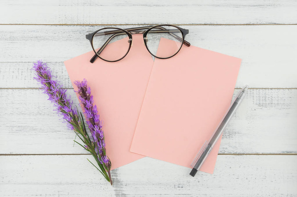 Puste karty różowe okulary oraz pióra ozdobiony liatris fioletowe kwiaty na białym tle drewna  - Zdjęcie, obraz
